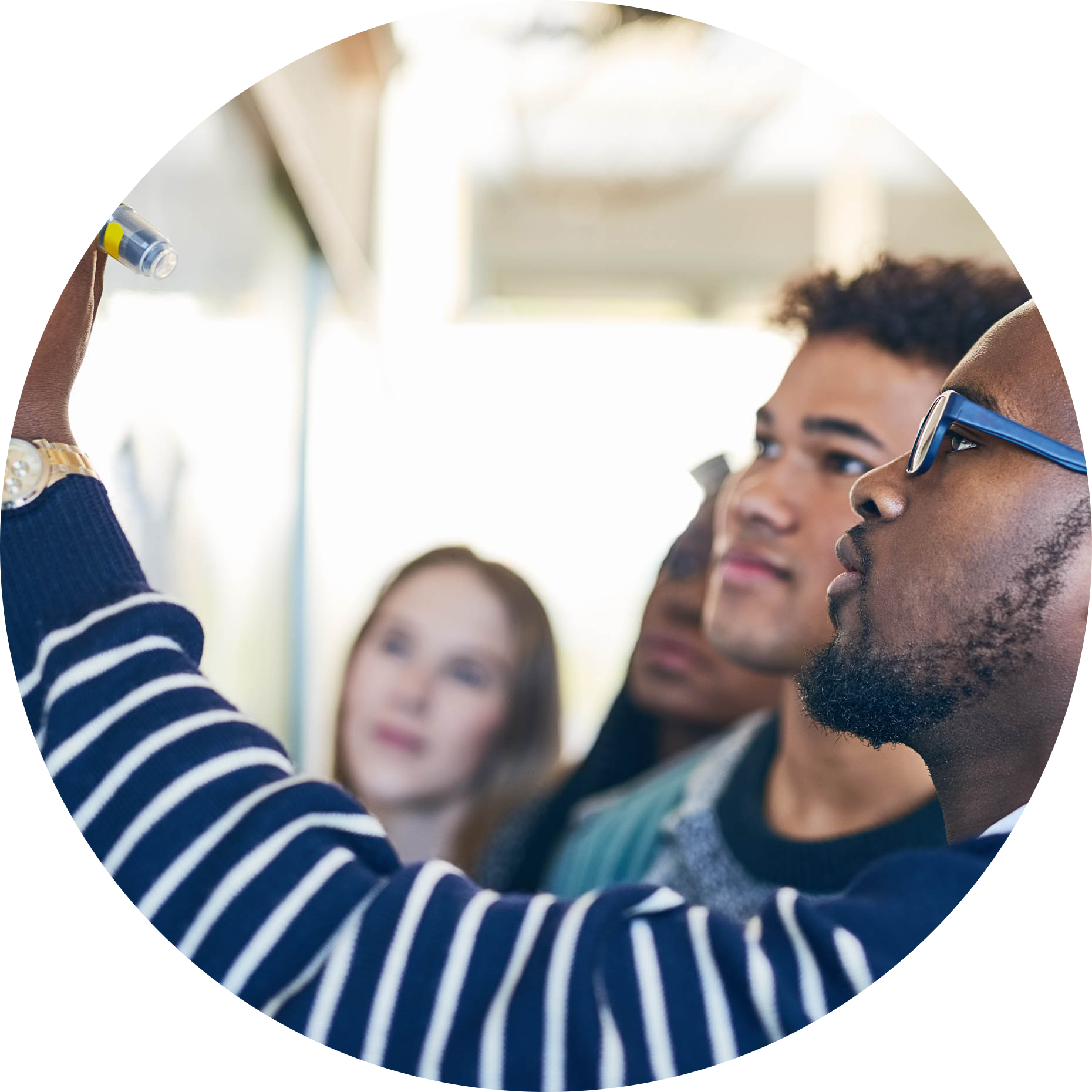 AdultLearners-056-Shot-of-a-young-man-writing-on-a-whiteboard-while-students-look-on-circle.png